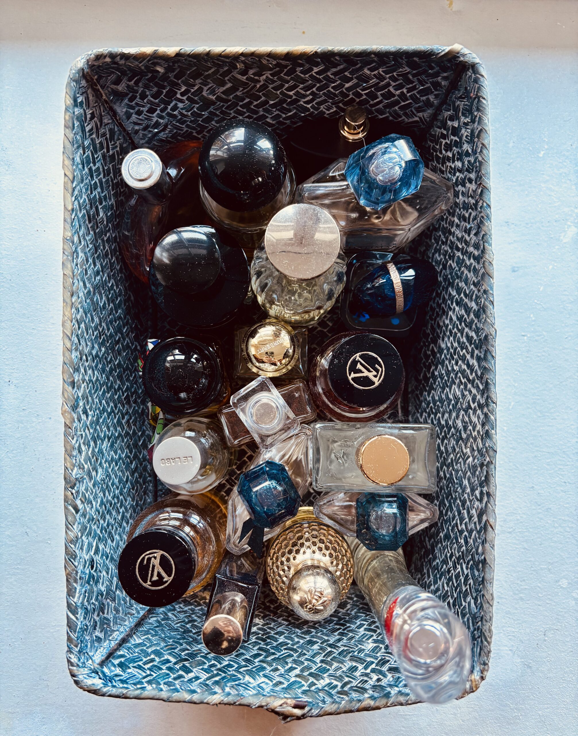 Un panier de flacons de ma collection personnelle de parfums, vu du dessus.